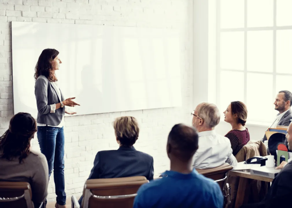 Eine Frau hält vor anderen Personen eine Präsentation in einem Meeting.