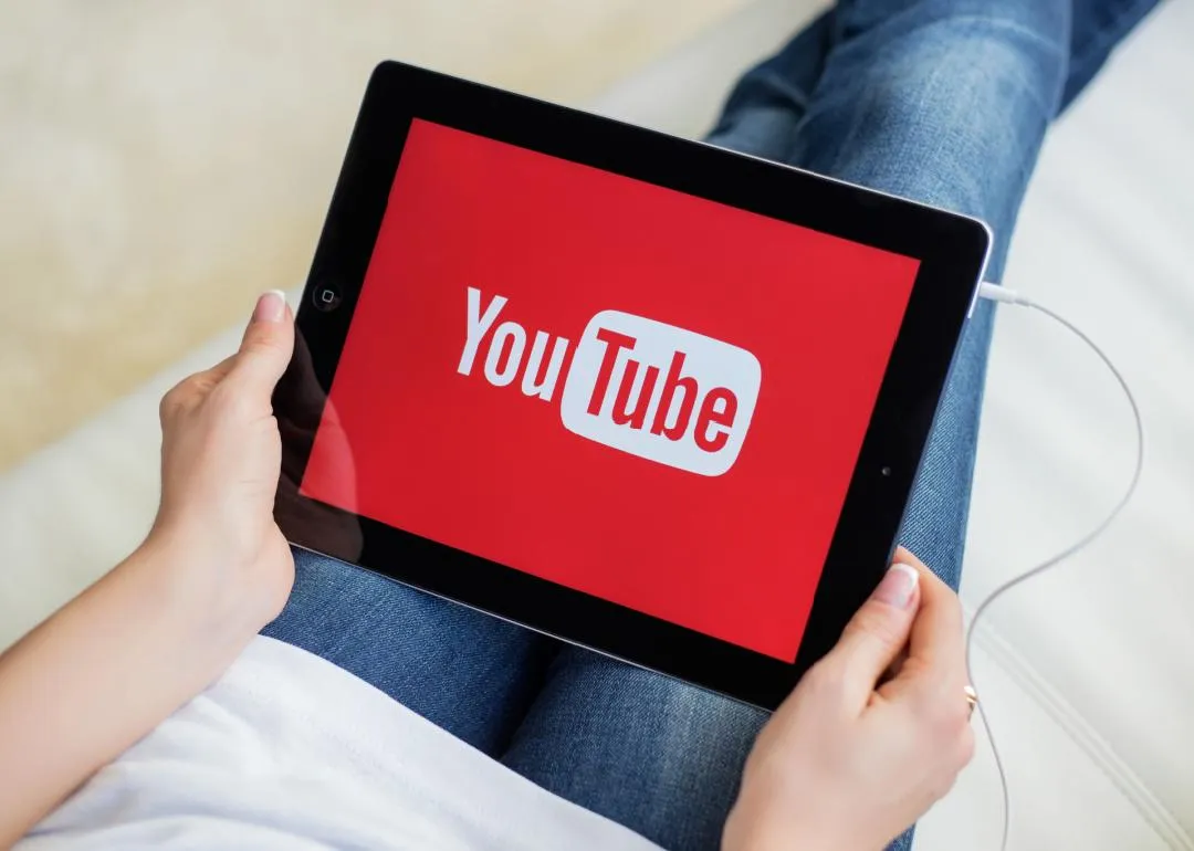 Une personne tenant un iPad avec YouTube à l'écran