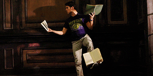 Homem lendo livros em cada mão