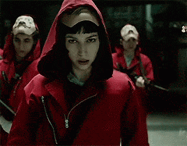 La casa de papel, mujer con capucha roja colocándose una máscara sobre el rostro.