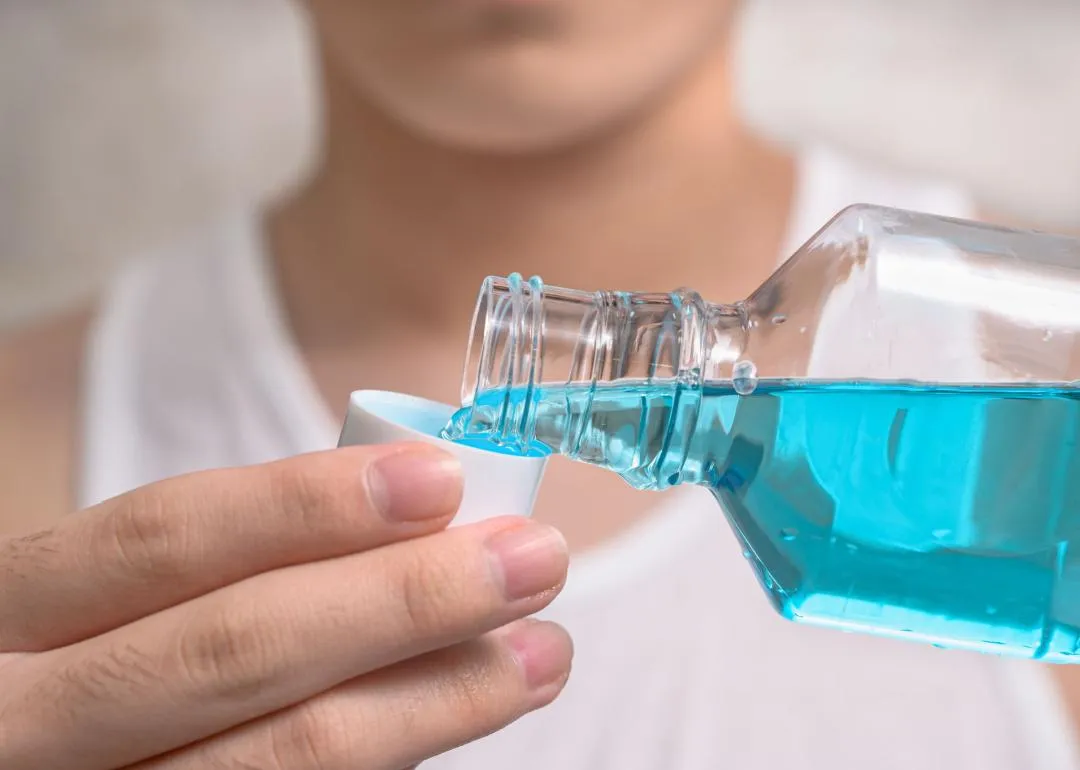Une personne versant du Listerine dans un bouchon