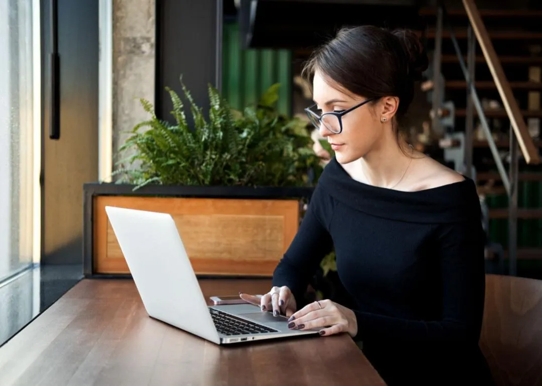 Uma mulher com óculos trabalhando em um laptop